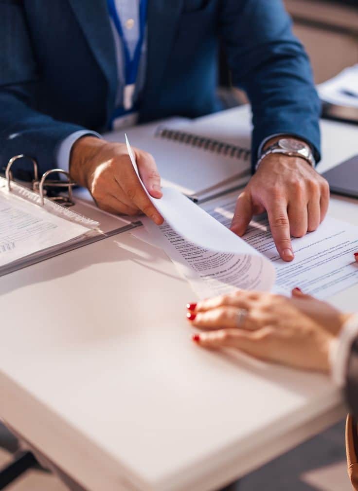 Duas pessoas sentadas à mesa analisando um documento impresso durante uma reunião